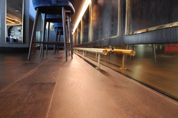 View of a wooden floor with a low angle, featuring stools and ambient lighting in a modern setting.