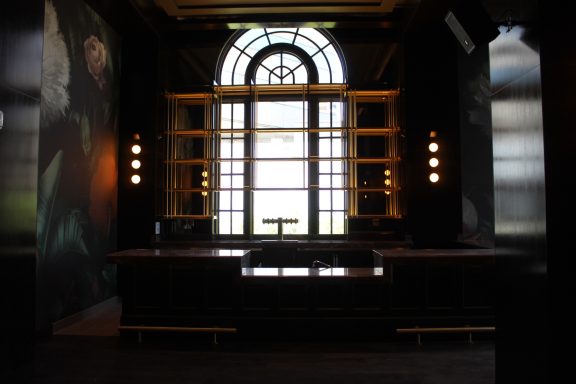 Modern interior with large window and illuminated shelves, dark walls, and minimalistic decor.