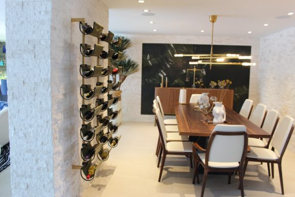Modern dining room with a wooden table, chairs, and a wine rack on the wall.