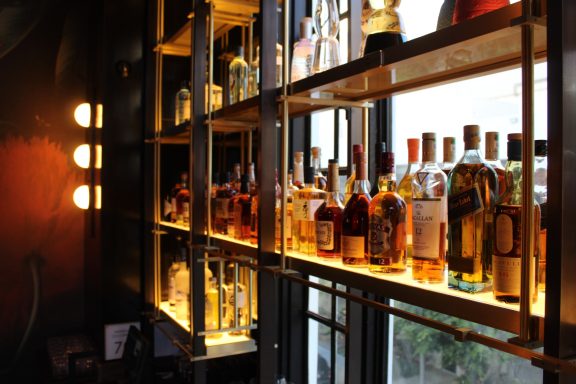 A well-lit bar shelves displaying various bottles of alcohol.