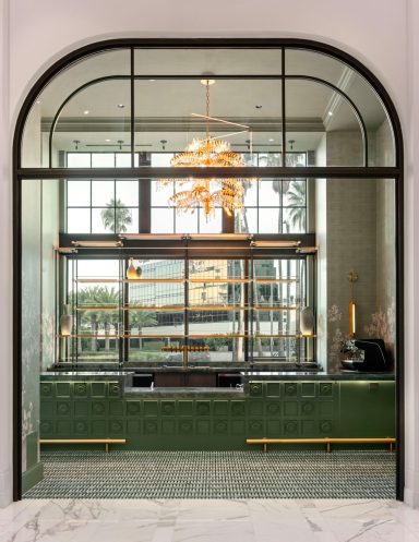 Modern interior showcasing a large window, decorative chandelier, and green marble accents.