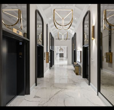 Modern corridor with elevators, marble floor, and stylish lighting fixtures.
