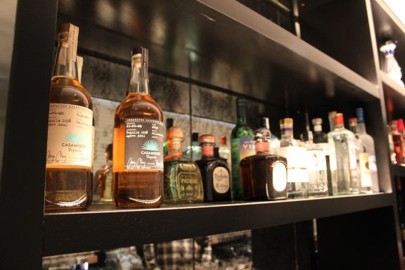 Collection of various liquor bottles on a black shelf.