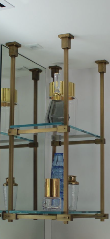 Metal and glass structure with gold accents, featuring shelves and a modern design.