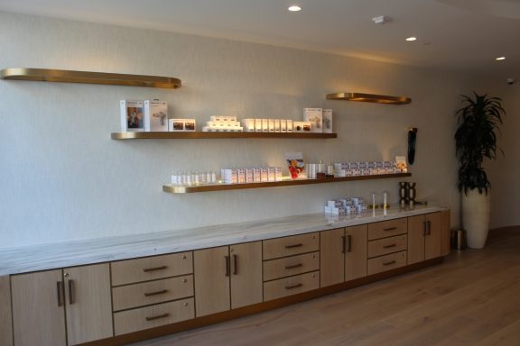 Modern spa interior with wooden cabinets and illuminated shelves displaying products.