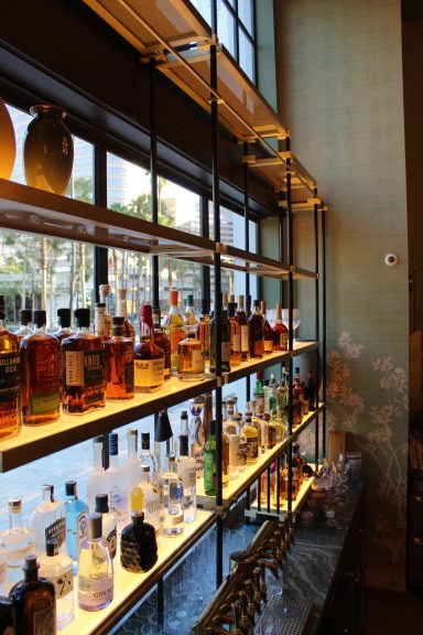 A stylish bar shelf displaying various bottles of liquor and glasses.