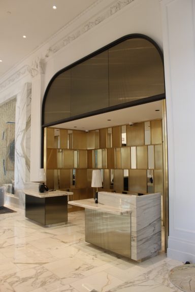 Modern lobby with a sleek reception desk and decorative golden wall accents.
