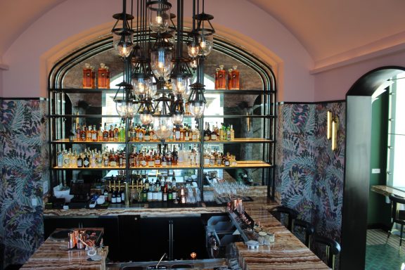 Elegant bar interior featuring shelves filled with various bottles and soft lighting.