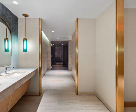 Modern bathroom featuring a marble sink, stylish lighting, and a hallway beyond.