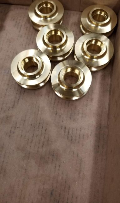 Brass mechanical washers arranged on a wooden surface.